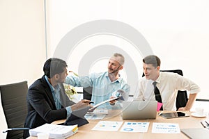 Investment advisor meeting of three businessmen analyzing company financial report,