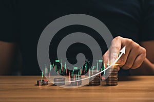 investment concept in financial business. Businessman`s hands with stacks of coins showing father graph chart with arrows