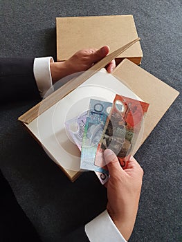 investment in education and knowledge, hands of a man with Australian money and books on the table