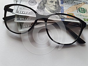 investment and promotion for a better vision, American banknotes of 100 dollars and black plastic frame glasses