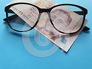 investment and promotion for a better vision, Singaporean banknote of two dollars and black plastic frame glasses