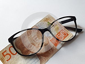 investment and promotion for a better vision, Swedish banknote of fifty kronor and black plastic frame glasses