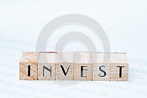 Investment, stock, bond or equity  concept, pen and wooden stamp block arrange the word INVEST on asset price numbers table report