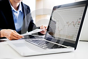 Investor analyzing financial reports of stock trading Market Graph investment charts on computer monitor screen in the office