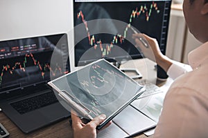 Investor man analyzing the graph of the stock market using a pen pointing to the computer screen