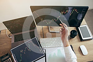 Investor man analyzing the graph of the stock market using a pen pointing to the computer screen