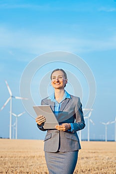 Investor in wind turbines with computer evaluating her investment on site