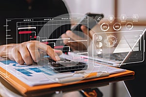 Investors working using calculator to calculate with smartphone, laptop the tax of static in office. Finance accounting concept