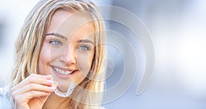 Invisalign orthodontics concept - Young attractive woman holding - using invisible braces or trainer