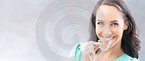 Invisalign orthodontics concept - Young attractive woman holding - using invisible braces or trainer photo