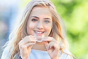 Invisalign orthodontics concept - Young attractive woman holding - using invisible braces or trainer photo