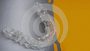 Invisible dental teeth brackets tooth aligners plastic braces retainers to straighten teeth on grey, orange background