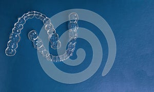 Invisible dental teeth brackets tooth aligners on trendy blue background, Plastic braces dentistry retainers to straighten teeth. photo