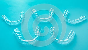 Invisible dental teeth brackets tooth aligners on turquoise background. Plastic braces dentistry retainers to straighten teeth