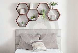 Inviting bedroom with suspended hexagonal shapes above the bed, beautifully accented by lush plants