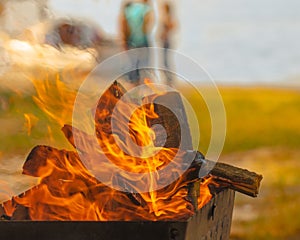 Inviting bonfire on the beach of the reservoir with yachts, people during the summer, bring back memories