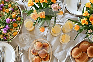 An inviting brunch setup with orange tulips, mimosas, and freshly baked rolls on a white tablecloth. This scene is ideal