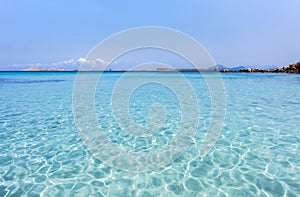 Inviting turquoise mediterranean sea with reflections - mountain range and rocks in the background, Capriccioli beach, Sardinia, I