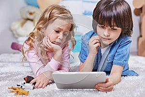 Involved boy and girl watching tablet in children room