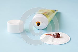 An iodine ointment on a cotton pad near an open tube over a blue background. The salve is used for small wounds and for skin