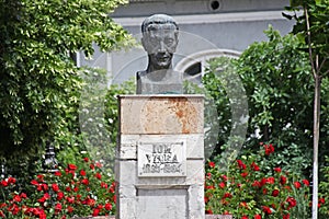 Ion Vinea statue with flowers and trees around photo