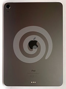 The iPad Air 2020 tablet in black color lies on a branded box on a white isolated background. Back side view of the tablet