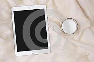 IPad Apple tablet with a candle. Elegant and cozy feminine background, concept for advertisement