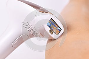 IPL `Intense Pulsed Light` laser hair removal home device next to bare leg photo