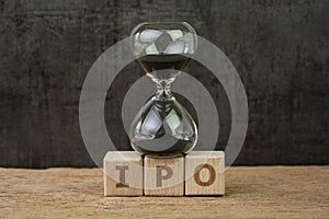 IPO, Initial Public Offering for company to buy and sell in stock market, sandglass or hourglass on wooden cube block with photo
