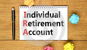 IRA individual retirement account symbol. Concept words IRA individual retirement account on white note on a beautiful wooden