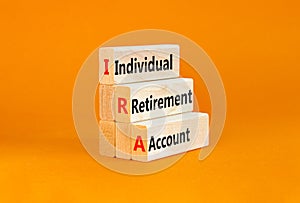 IRA individual retirement account symbol. Concept words IRA individual retirement account on wooden blocks on beautiful orange