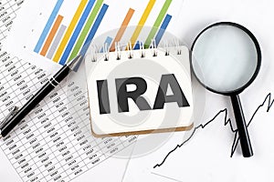 IRA text on notebook on the graph background with pen and magnifier