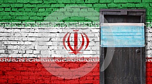Iran flag painted on brick wall and closed door with medical mask protected
