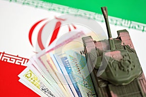 Iranian army toy tank drive on iranian bills of rial currency on flag of Islamic Republic of Iran