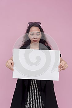 An irate southeast asian lady with wavy hair holding a blank white cardboard sign. For a protest, complaint or opposition.