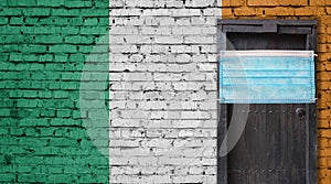 Ireland flag painted on brick wall and closed door with medical mask protected