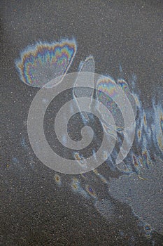 Iridescent spot of gasoline. Petrol on the asphalt a big polluted puddle water. A rainbow slick of gasoline