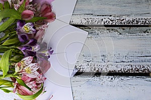 Iris flowers lie on a notepad, white sheets of paper, on a white wooden background, layout.