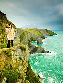 Irish atlantic coast. Woman tourist standing on rock cliff