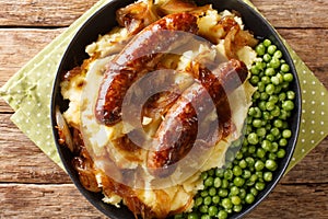 Irish Bangers and Mash is a dish consisting of sausages served with mashed potatoes and onion gravy closeup in the plate.