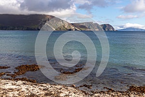 Irish beach with sand and seaweed and mountains in background