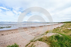 Irish Coastal Beauty: Sandy Dunes, Lush Vegetation, Azure Sea, and Majestic Mountains