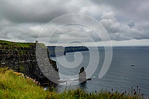 Irish landscape of the Branaunmore sea stack and a boat sailing in the ocean in the Cliffs of Moher