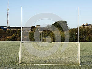 Irish sport training ground with tall goal posts for camogie, Gaelic football and rugby on a cold winter day. Frost on the green