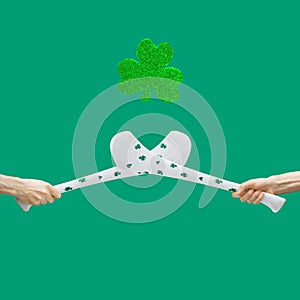 Irish traditional sport minimal concept. Man hands hold criss-crossed two hurly sticks â€“ hurleys in white color with shamrock