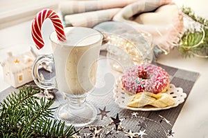 Irish traditional winter cream cocktail eggnog in a glass mug with milk, rum and cinnamon, banana covered with whipped cream,