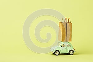 Irkutsk, Russia - October 03, 2020: Light green retro toy car carries paper shopping bags. Eco goods delivery concept