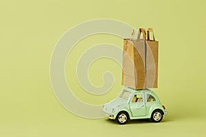 Irkutsk, Russia - October 03, 2020: Light green retro toy car carries paper shopping bags. Eco goods delivery concept