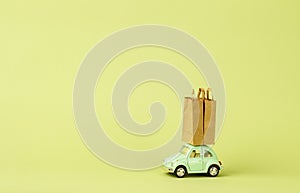 Irkutsk, Russia - October 03, 2020: Light green retro toy car carries paper shopping bags. Eco goods delivery concept