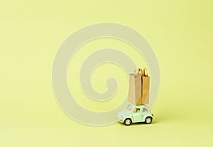 Irkutsk, Russia - October 03, 2020: Light green retro toy car carries paper shopping bags. Eco goods delivery concept